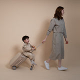 Woman and child in matching outfits with a suitcase on a beige background