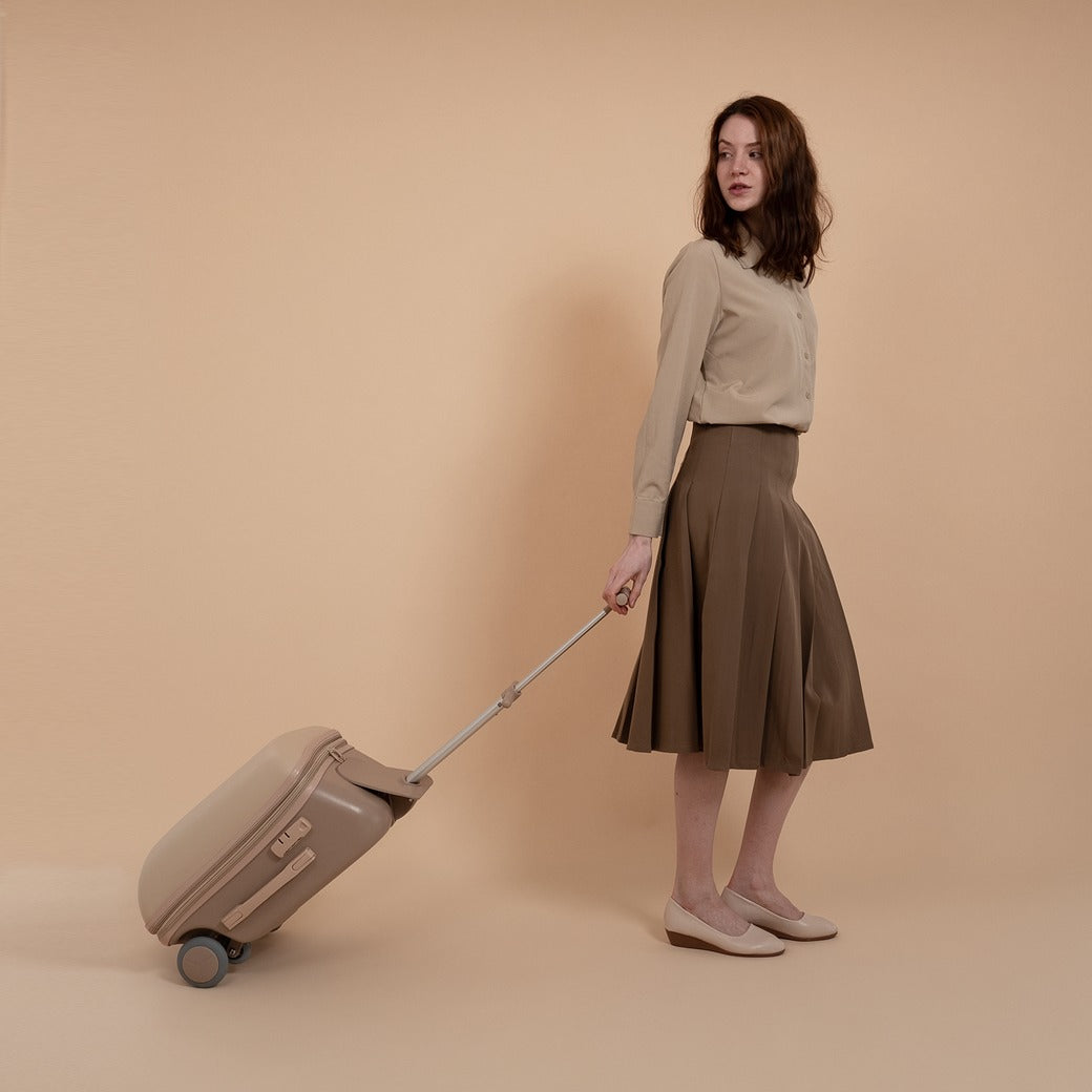 Woman with a beige suitcase against a beige background