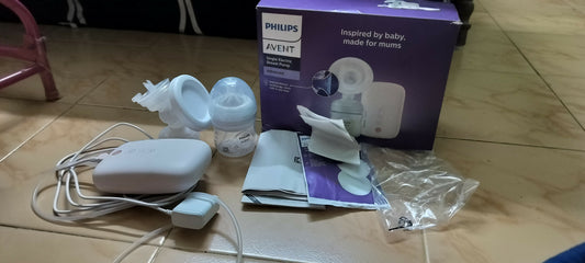Philips Avent breast pump set on a wooden floor with packaging.
