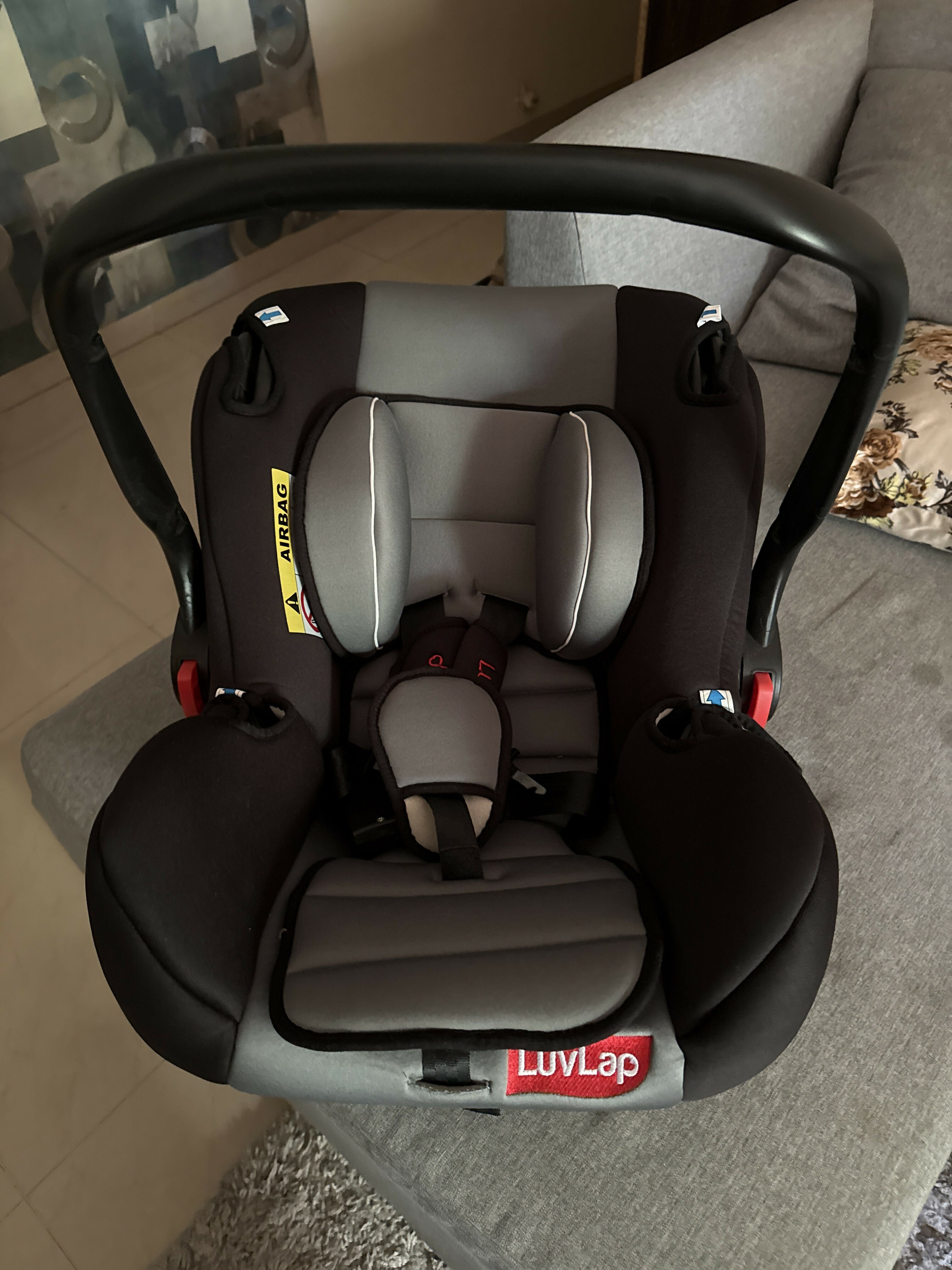 LuvLap 4-in-1 infant car seat and carry cot with canopy in black, featuring a 5-point safety harness, rocking and feeding chair modes, cushioned seating, and a carry handle for babies from birth to 15 months (up to 13 kg).