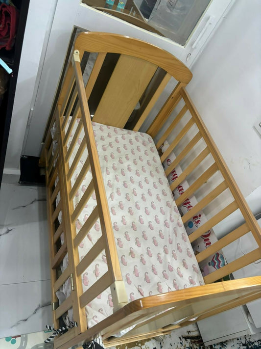 Wooden crib with a patterned mattress in a room setting