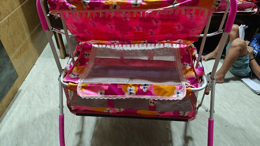 Multicolored baby crib with pink frame on a tiled floor.