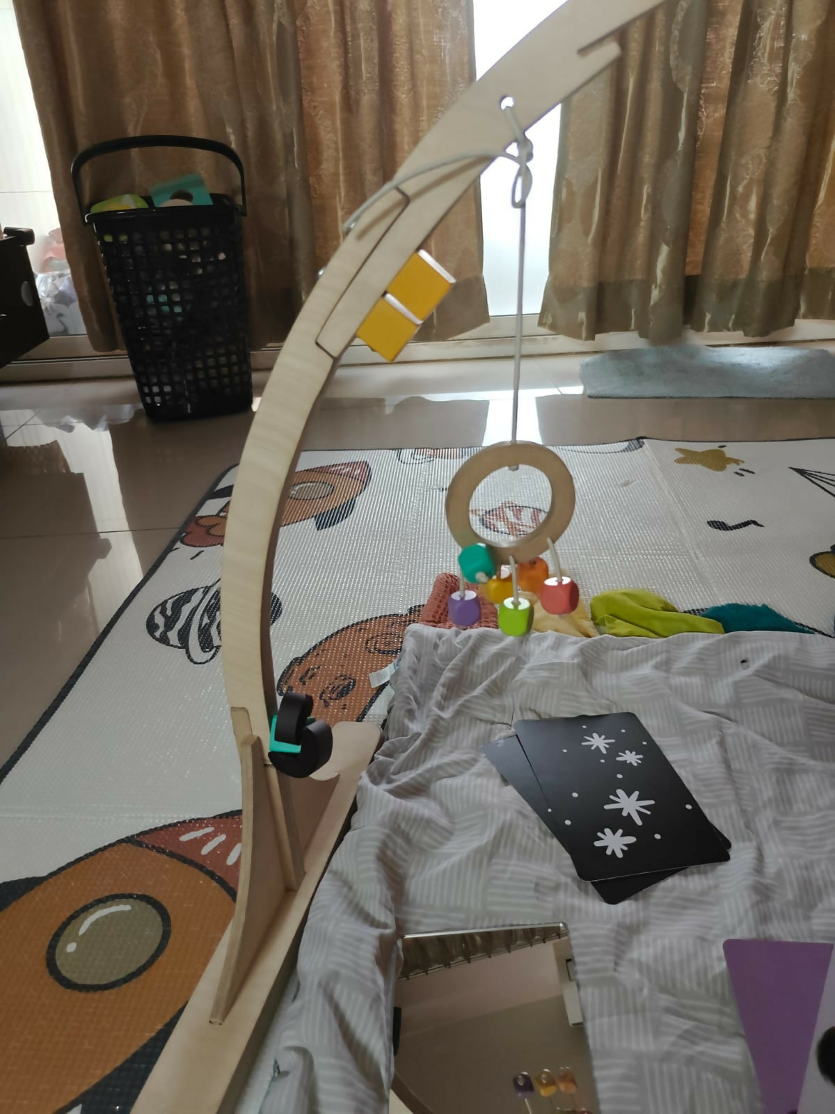Baby playpen with toys and cards on a colorful mat