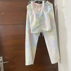 Colorful tie-dye outfit hanging on a hanger against a wooden door.