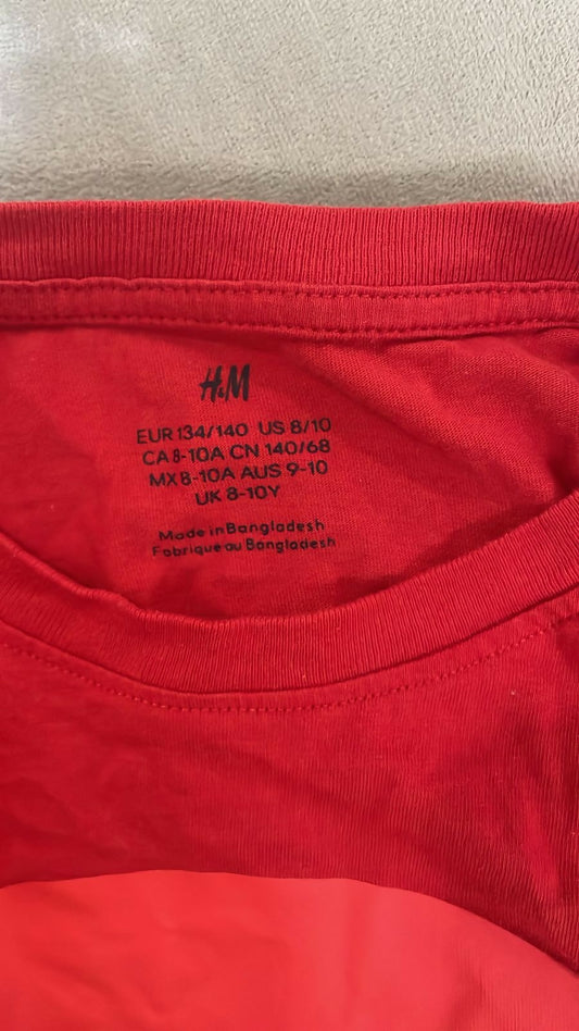 Red garment with H&M label and size information on a beige background