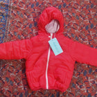 Vibrant red puffer jacket with hood for kids, featuring warm padded insulation, lightweight construction, front zip closure, and a cozy design for comfortable winter wear.