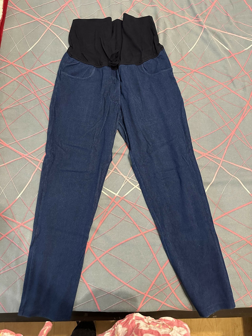 Blue pants with a black waistband on a patterned surface