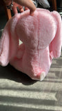 Pink plush toy held by a hand on a textured surface