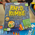 Hand holding a 'Rapid Rumble' game box with colorful dice illustration 