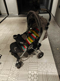 Stroller with a colorful striped bag on a patterned floor