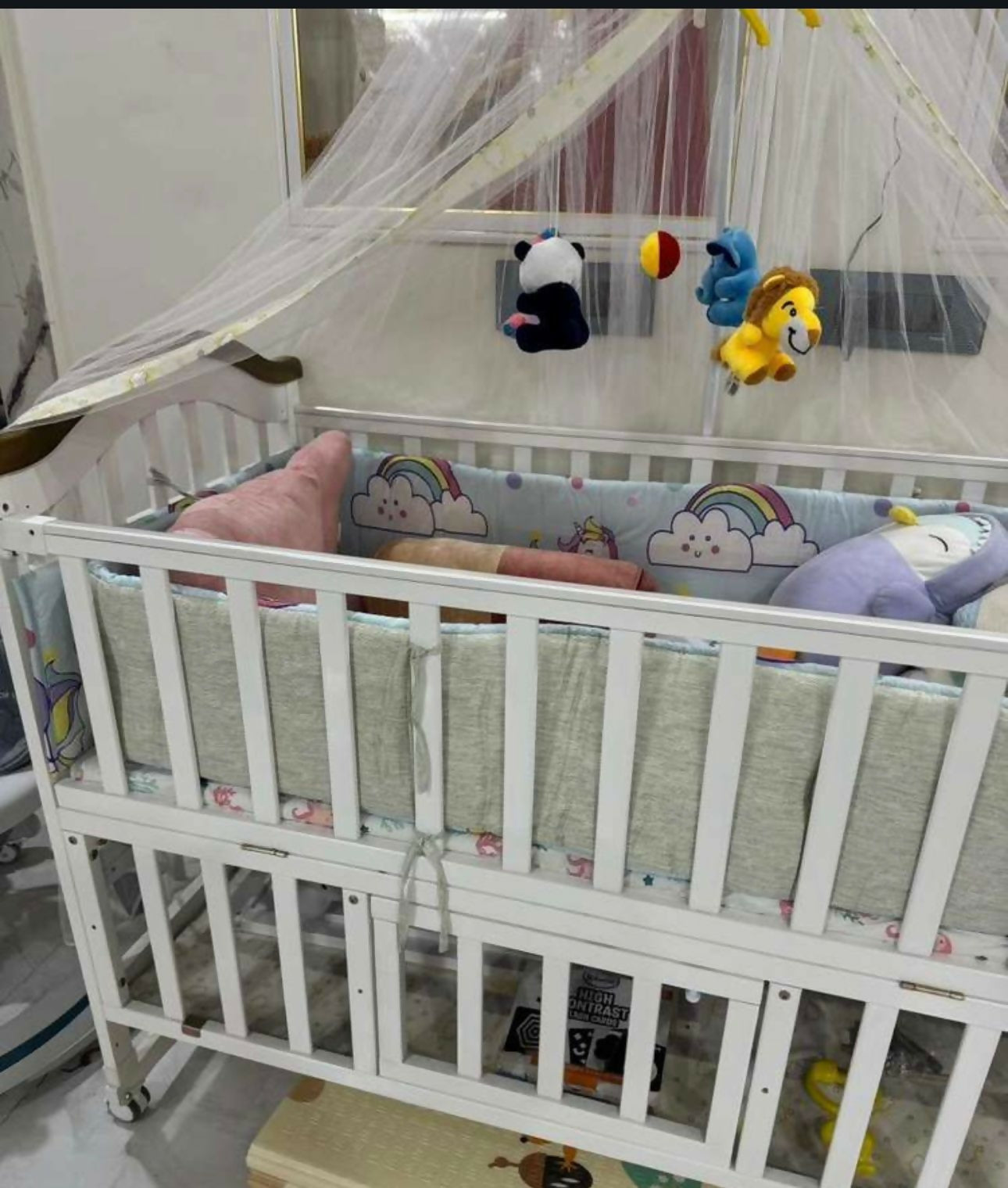 White crib with baby toys and bedding in a room setting
