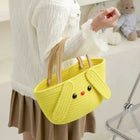 Person holding a yellow knitted bag shaped like a dog with a teddy bear in the background.