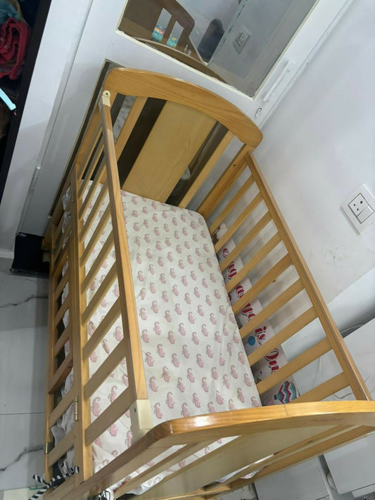Wooden crib with a patterned mattress in a room setting