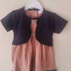 Children's outfit with black top and pink shorts on a hanger against a white background
