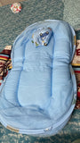 Blue baby crib with plush toy on a patterned surface