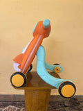 Colorful children's balance bike on a wooden surface with a yellow wall background