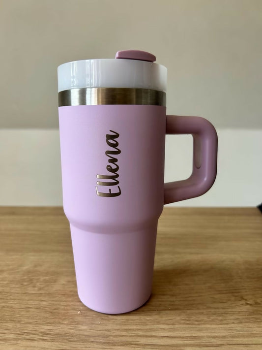 Pink travel mug with a handle on a wooden surface