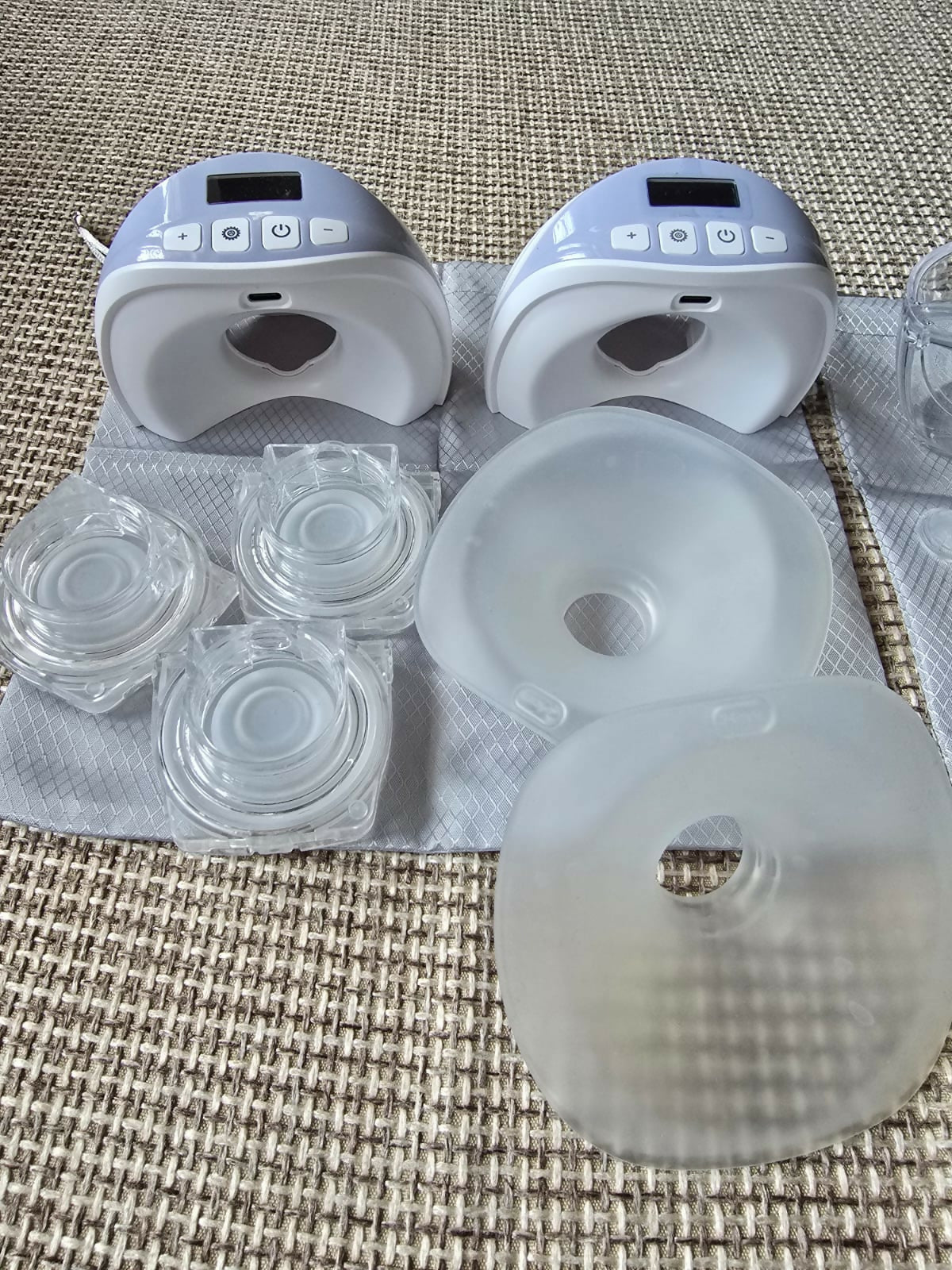 Two breast pumps with additional parts on a textured surface