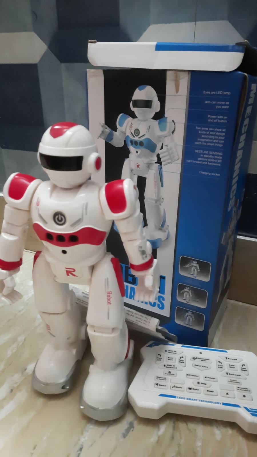 White and red robot toy with blue and white box in the background