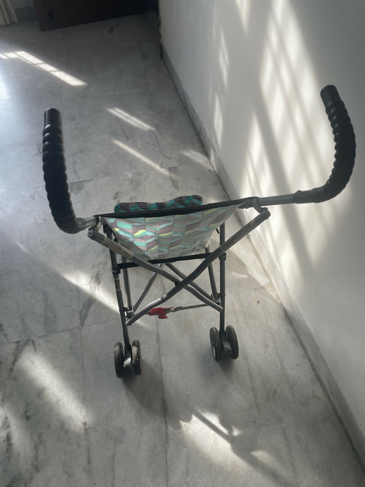 Small child's stroller with a reflective surface on a marble floor.