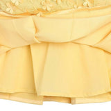 Close-up of a yellow dress with floral embroidery on a white background