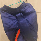 Blue jacket with a red zipper on a hanger against a tiled wall.