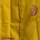 Yellow garment with a floral pocket and embroidered design on a yellow background