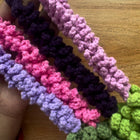 Colorful crocheted headbands on a wooden surface