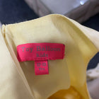 Close-up of a pink label on a yellow garment with a blurred background