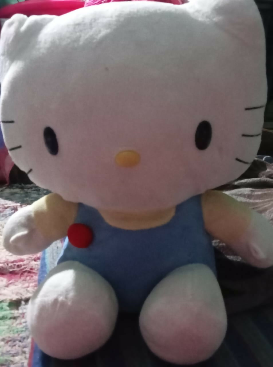 Plush toy resembling a character with a blue outfit and red bow tie on a textured surface.