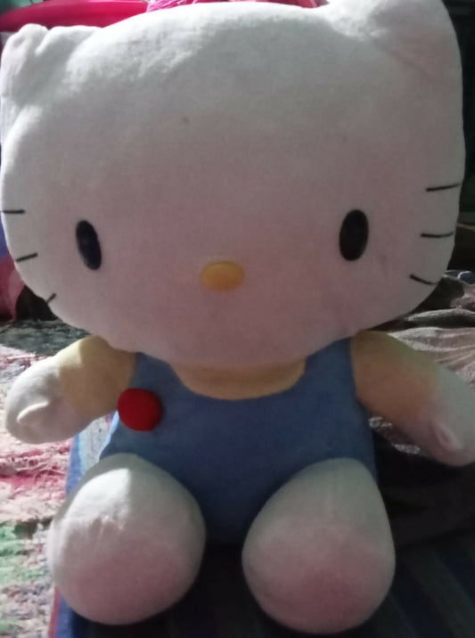 Plush toy resembling a character with a blue outfit and red bow tie on a textured surface.