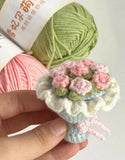 Handmade crochet flower arrangement with pink and green yarn on a white background