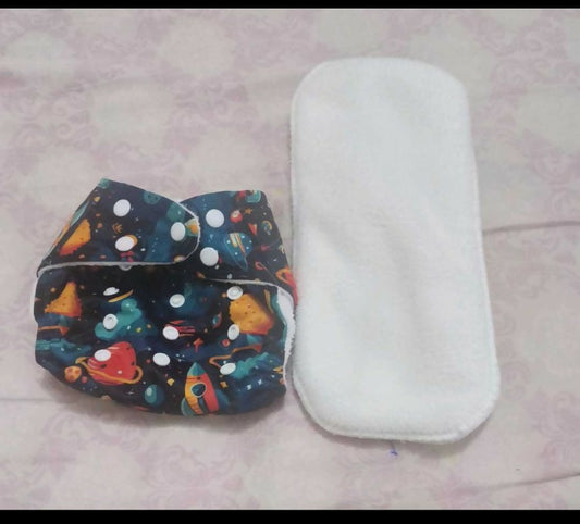 Colorful diaper with space design and white diaper cover on a light pink surface