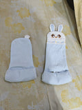 Pair of white gloves with bunny ears on a floral fabric background