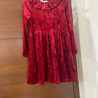 Red velvet dress hanging on a wooden door