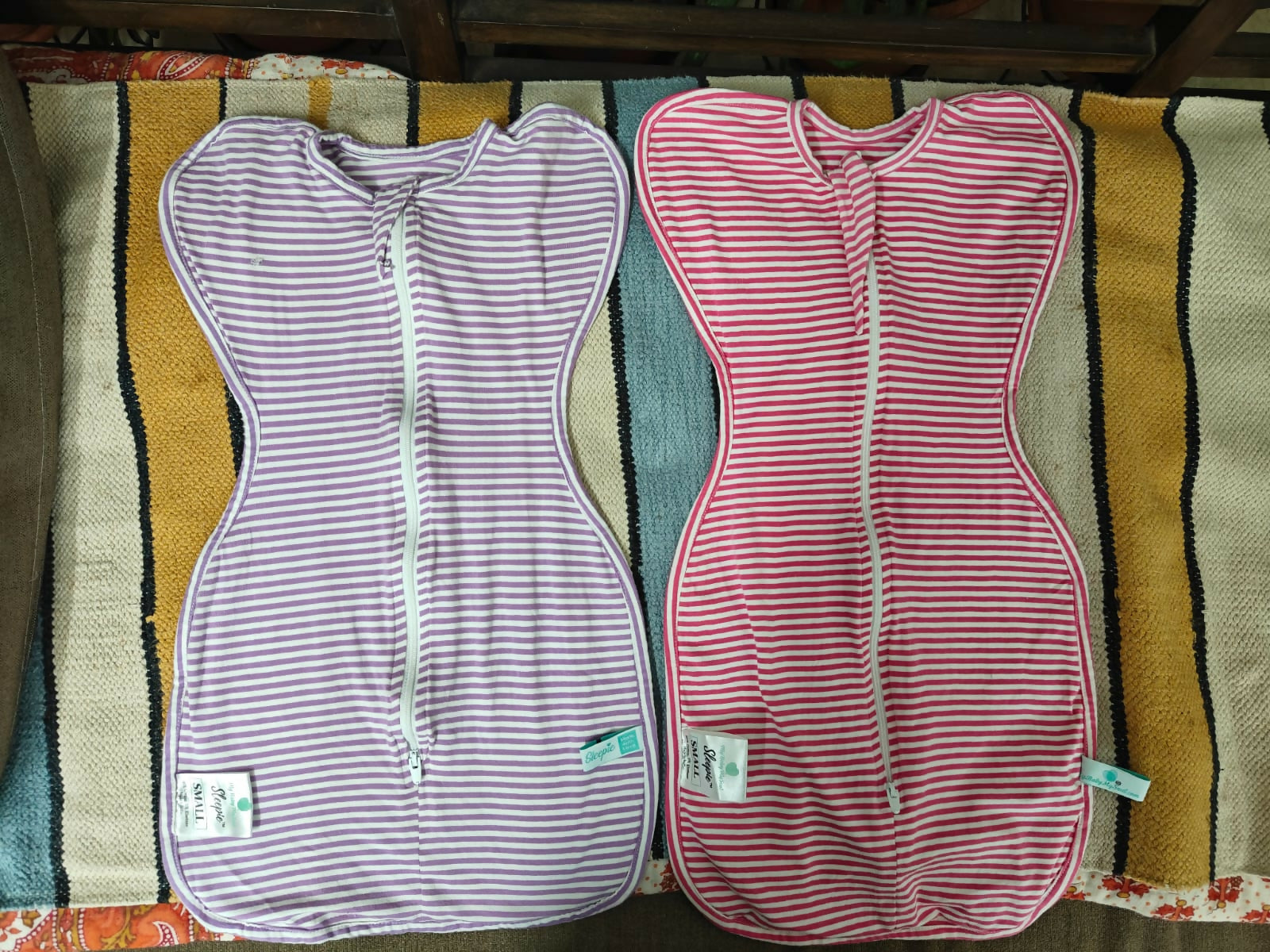 Two striped baby wraps, one pink and white, one purple and white.