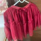 Red dress with ruffled sleeves and bottom hanging on a hanger against a wooden door.