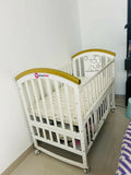 Shop Huny Huny Convertible Baby Cot – Wooden crib with storage, teething rails, wheels, and adjustable height.
