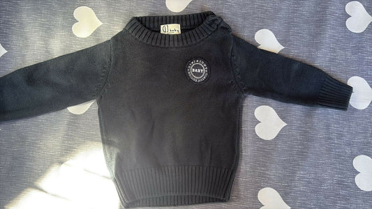 Black sweater with a logo on a gray surface with heart patterns