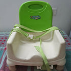 Green and white baby booster seat on a checkered tablecloth