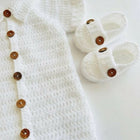 White baby outfit with buttons and white baby shoes 