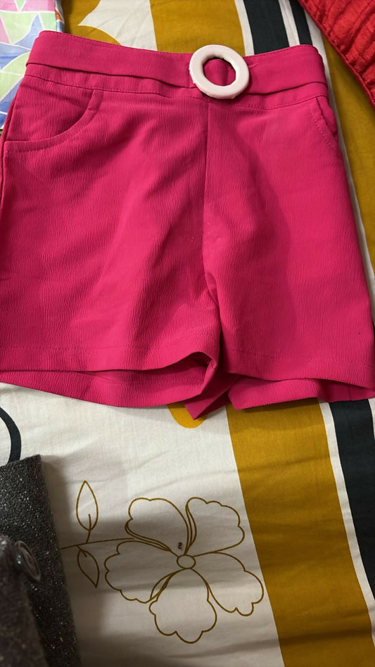 Pink shorts with a wooden ring on a patterned fabric background