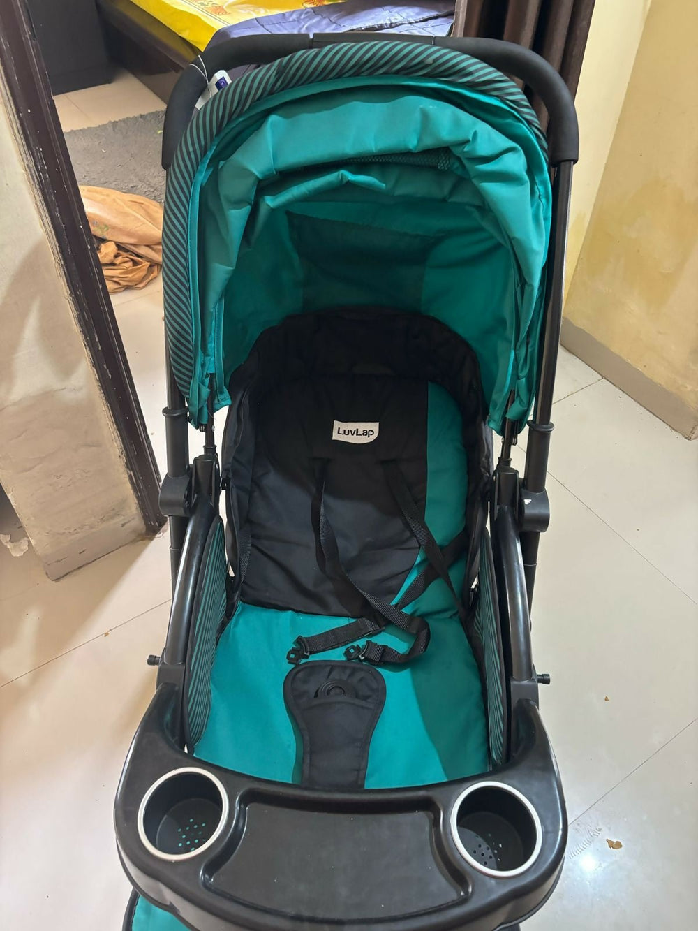Teal and black stroller on a tiled floor