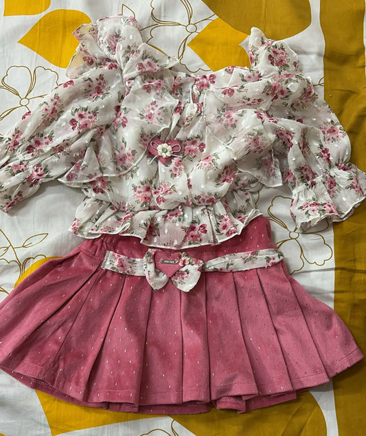 Floral top and pink skirt set on a patterned fabric background