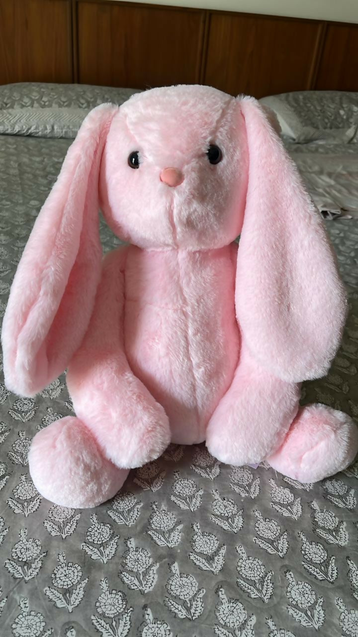 Pink plush bunny toy on a patterned surface