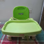 Green high chair on a checkered floor with a white wall background