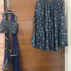 Blue patterned top and skirt set hanging on a wooden door.