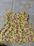 Yellow dress with pink floral pattern on a floral-patterned surface