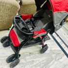 Red and gray stroller on a marble floor with a couch in the background