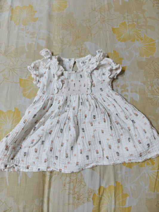 White baby dress with floral pattern on a yellow floral background